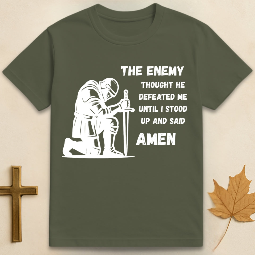 Green Amen t-shirt featuring kneeling soldier graphic with sword planted in the ground and text "The enemy thought he defeated me until I stood up and said Amen".