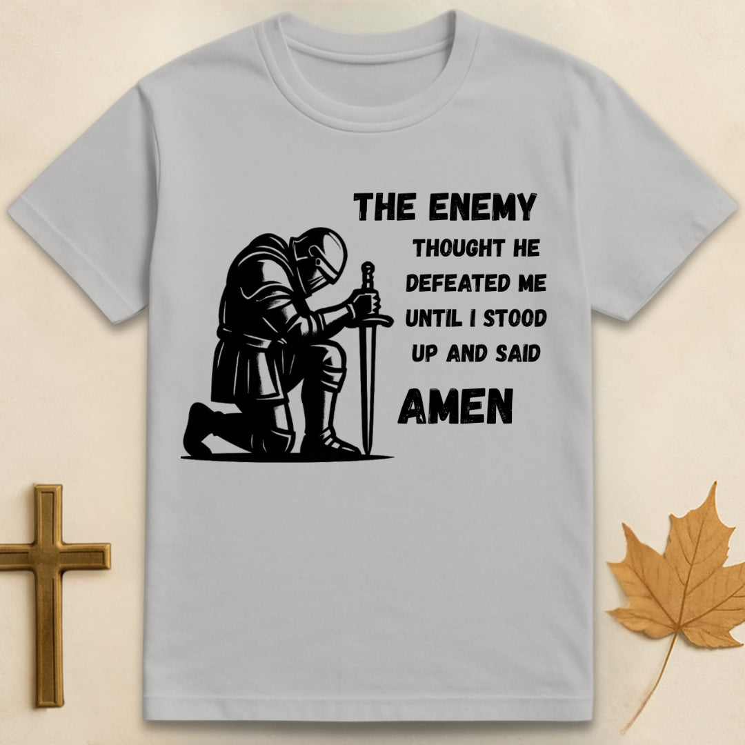 Ice grey Amen t-shirt featuring kneeling soldier graphic with sword planted in the ground and text "The enemy thought he defeated me until I stood up and said Amen"